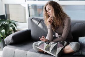 woman sitting on couch and staring blankly into space ass he struggles with living with anxiety