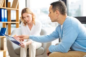 young couple seated in office looking over literature for a psychotherapy program