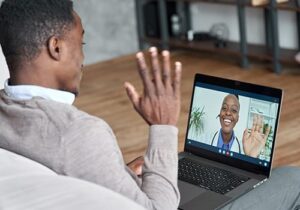 young man sitting on his couch at home participating virtually in a ptsd treatment program