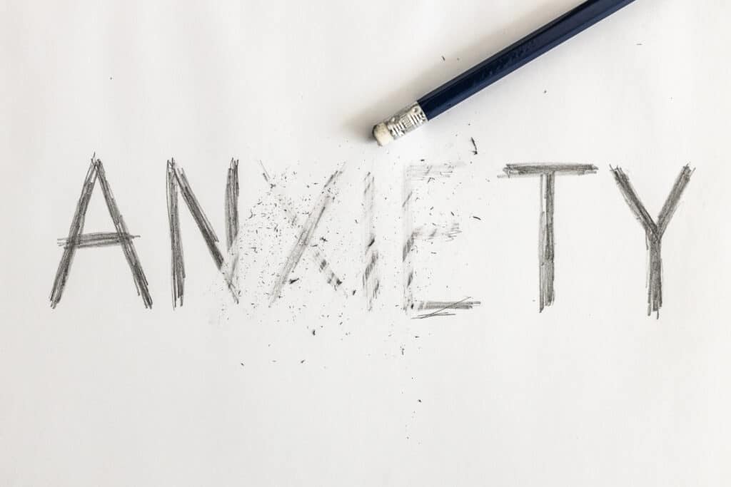 Erasing anxiety. Anxiety written on white paper with a pencil, partially erased with an eraser. Symbolic for overcoming anxiety or treating anxiety.